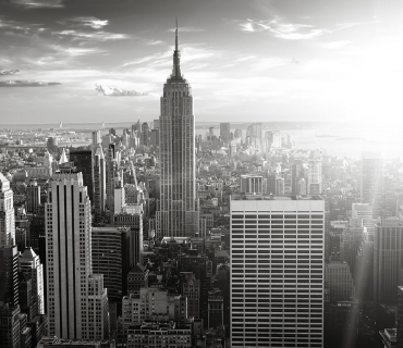 Black and white photo of New York City's Empire State Building with the sun shining behind it.